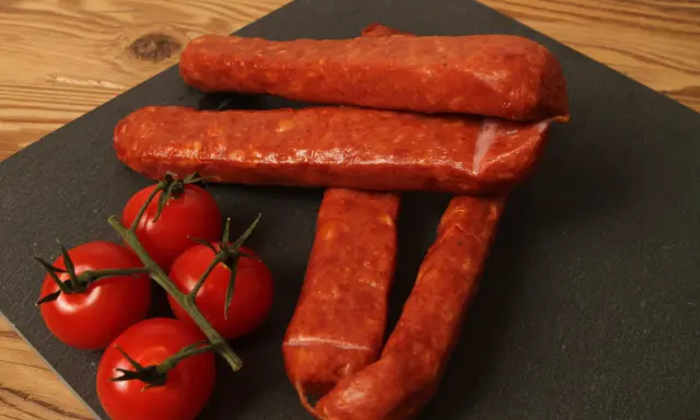 Saucisses sèches et tomates cerises sur une planche d'ardoise, parfait pour une recette de saucisse gendarme.