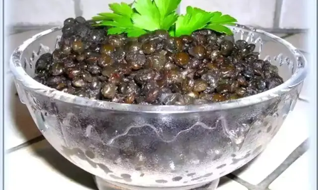 Lentilles beluga, parfaitement cuites, servies dans un bol en verre, garnies de persil frais. Un délice simple et sain.
