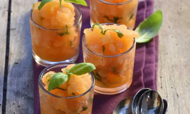 Recette soupe de melon apéritif : sorbet de melon frais aux feuilles de basilic dans des verres, prêt à déguster.