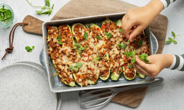 Courgettes farcies à la viande hachée, gratinées au fromage et garnies de feuilles de basilic frais. Un plat savoureux prêt à être dégusté.