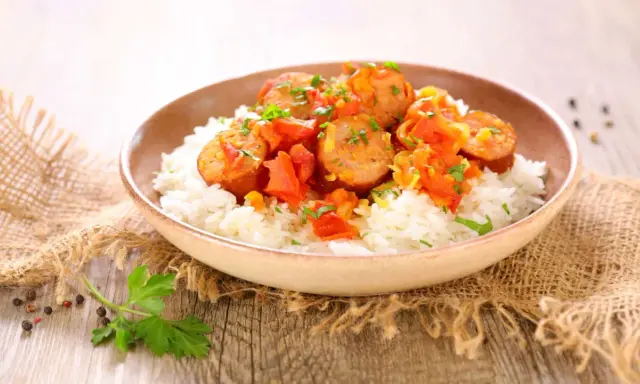 Un plat de rougail saucisse sur du riz blanc, garni de persil. Quel vin avec rougail saucisse ? Un vin fruité et léger serait parfait.