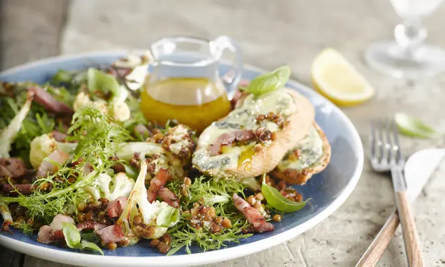 Salade verte avec chou-fleur rôti, lentilles, lardons et toasts au fromage bleu. Une idée de quoi mettre dans une salade verte pour un repas savoureux.