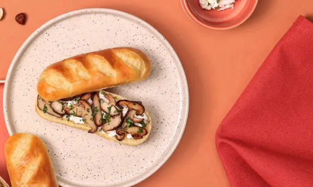 Délicieux sandwich pain au lait garni de champignons sautés et de fromage frais, parsemé de persil.