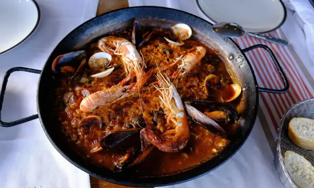 Un plat de vin avec paella aux crevettes et moules, prêt à être dégusté.