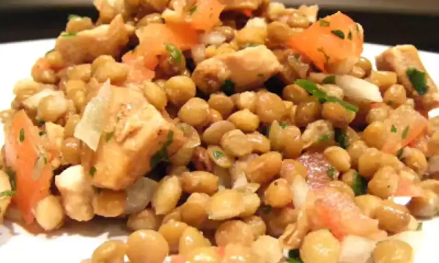 Salade de lentilles et poulet, garnie de dés de tomates et d'herbes fraîches. Un plat sain et savoureux.