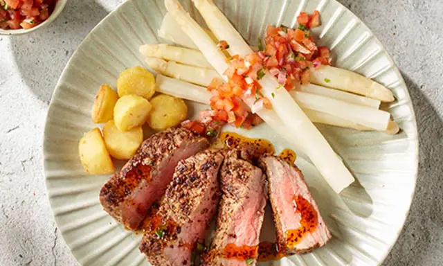 Tranches de viande juteuse avec asperges blanches et pommes de terre sautées, un accompagnement parfait pour un repas savoureux.