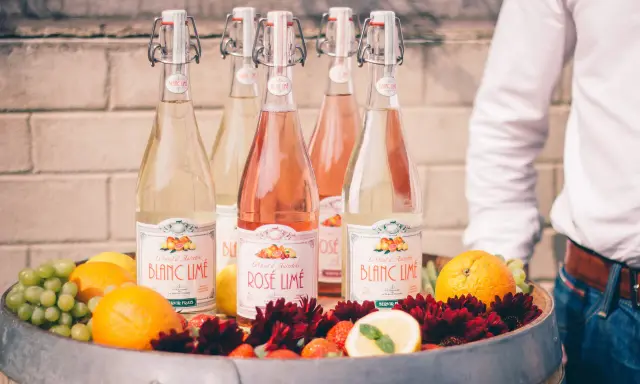 Bouteilles de cocktail vin blanc limonade citron, fruits frais et fleurs dans un tonneau.