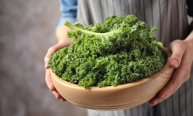 Un bol en bois rempli de chou kale frais, prêt pour une délicieuse recette italienne.