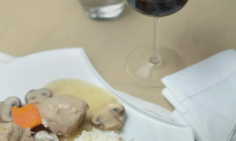 Un verre de vin rouge accompagne une blanquette de veau avec riz et champignons. Quel vin avec une blanquette de veau ?