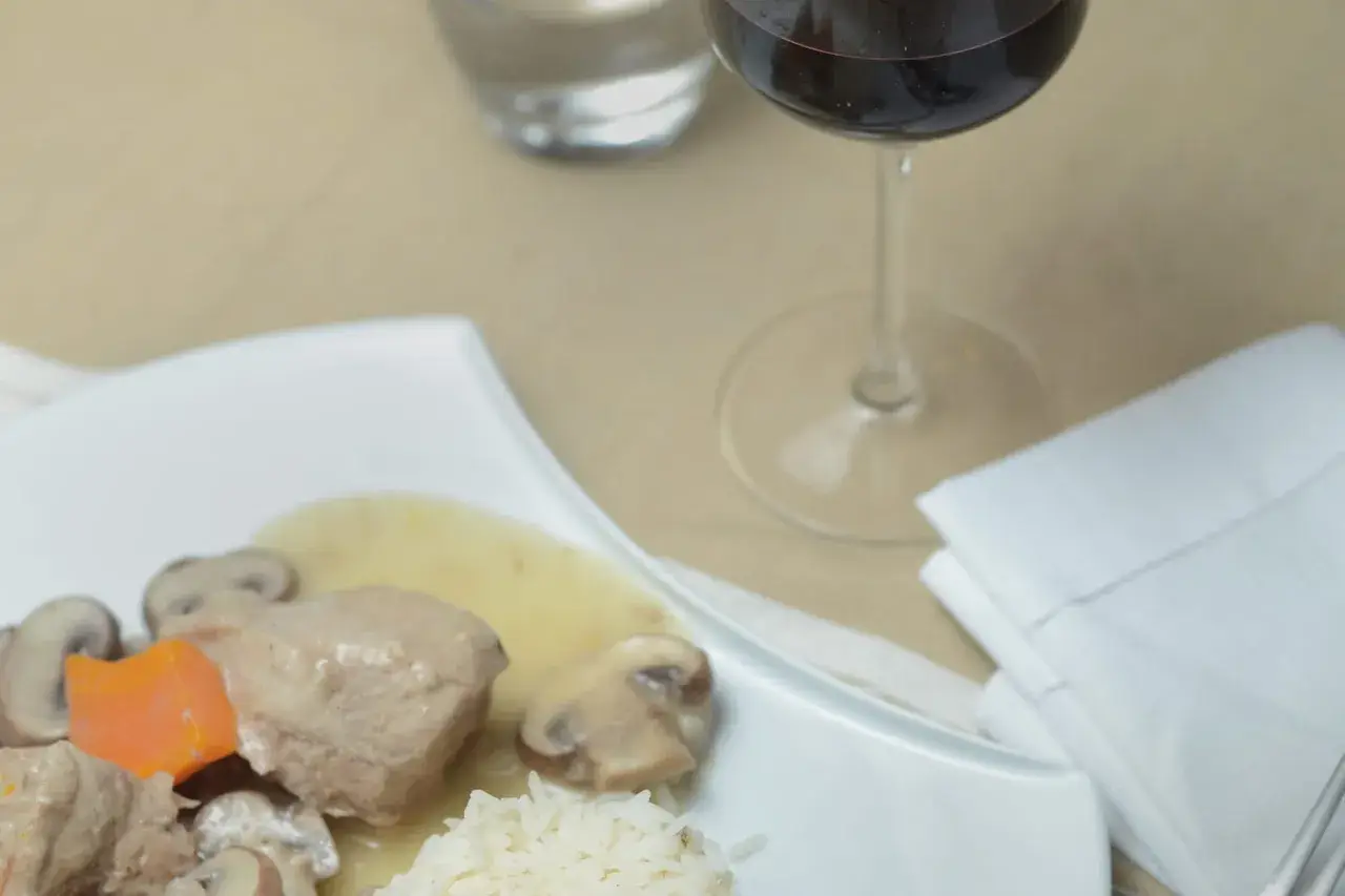 Un verre de vin rouge accompagne une blanquette de veau avec riz et champignons. Quel vin avec une blanquette de veau ?