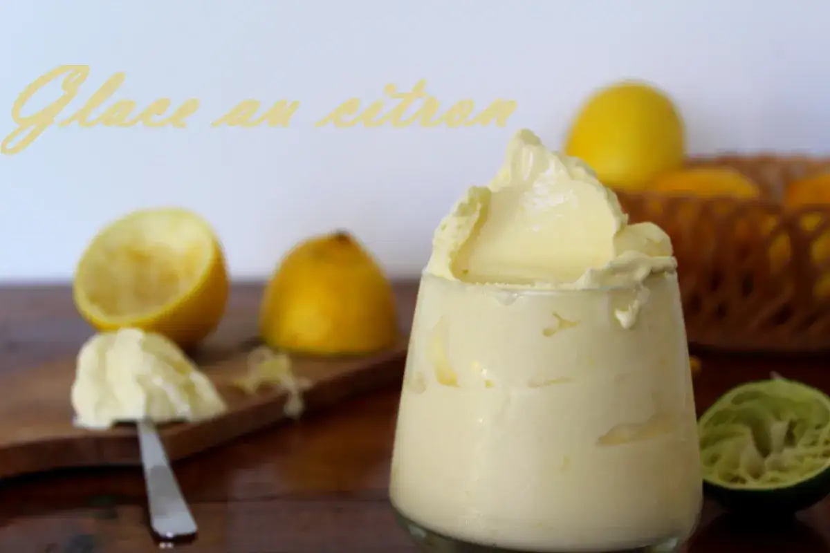Glace au citron onctueuse, servie dans un verre, avec des citrons frais et une râpe à citron en arrière-plan.