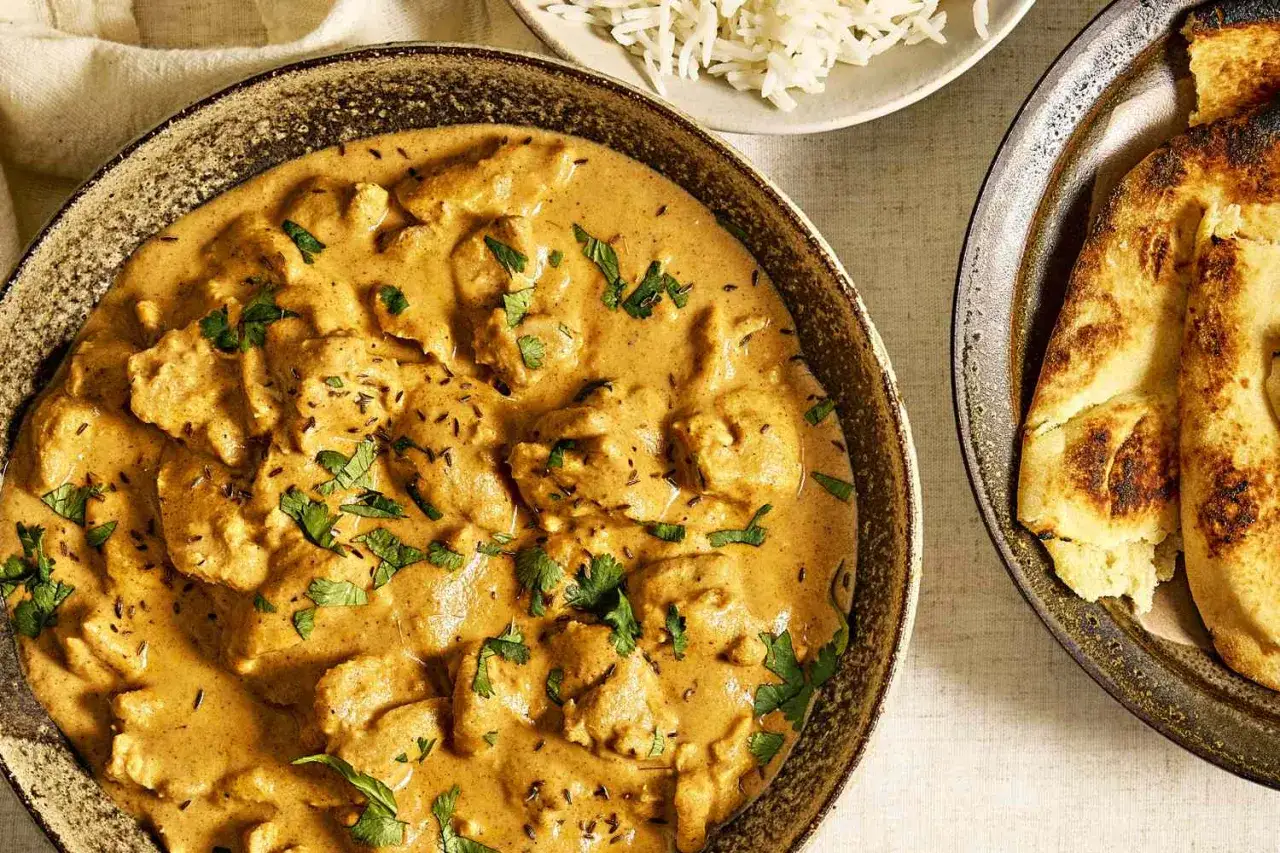 Un délicieux poulet korma recette, crémeux et parfumé, servi avec du riz basmati et du pain naan grillé.