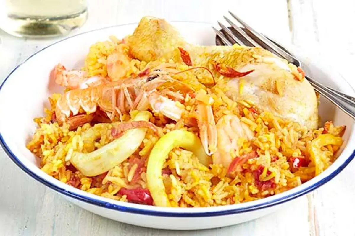 Un plat de vin avec paella, garni de crevettes, de langoustines et de poulet.
