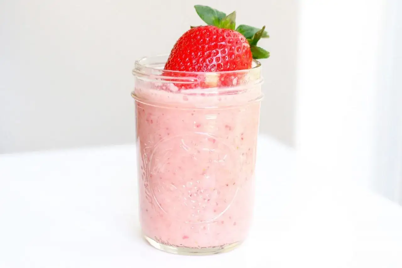 Un délice rose et frais : un smoothie sans lait aux fraises, garni d'une fraise entière. Parfait pour une pause légère et fruitée.