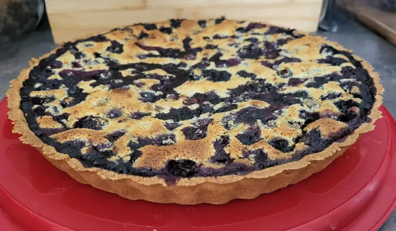 Tarte myrtille amande dorée, avec une croûte croustillante et une garniture généreuse de myrtilles et d'une touche d'amande.