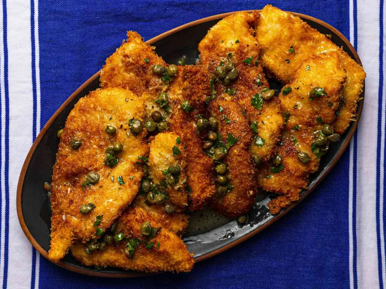 Escalopes de poulet panées, dorées et croustillantes, nappées d'une sauce citronnée aux câpres. Une recette simple et savoureuse.