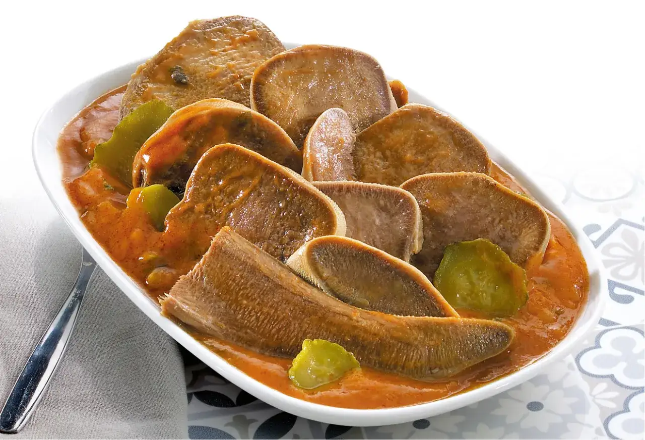 Langue de bœuf en sauce piquante, garnie de cornichons croquants. Un plat savoureux et réconfortant.