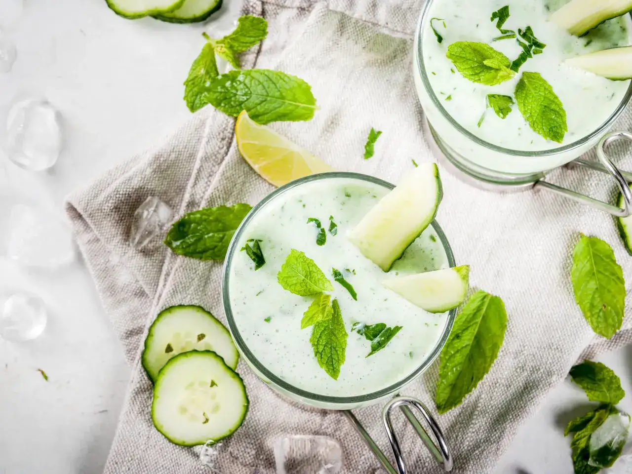 Deux verres de soupe de concombre froide, garnie de menthe fra&icirc;che et de fines tranches de concombre, sur un tissu de lin.