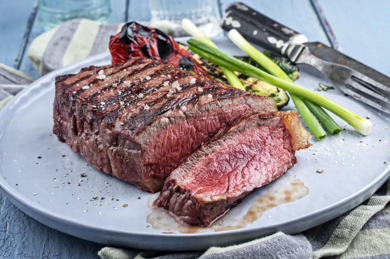 Un succulent rumsteck de boeuf grillé, coupé en tranches, servi avec des légumes rôtis et des oignons verts.