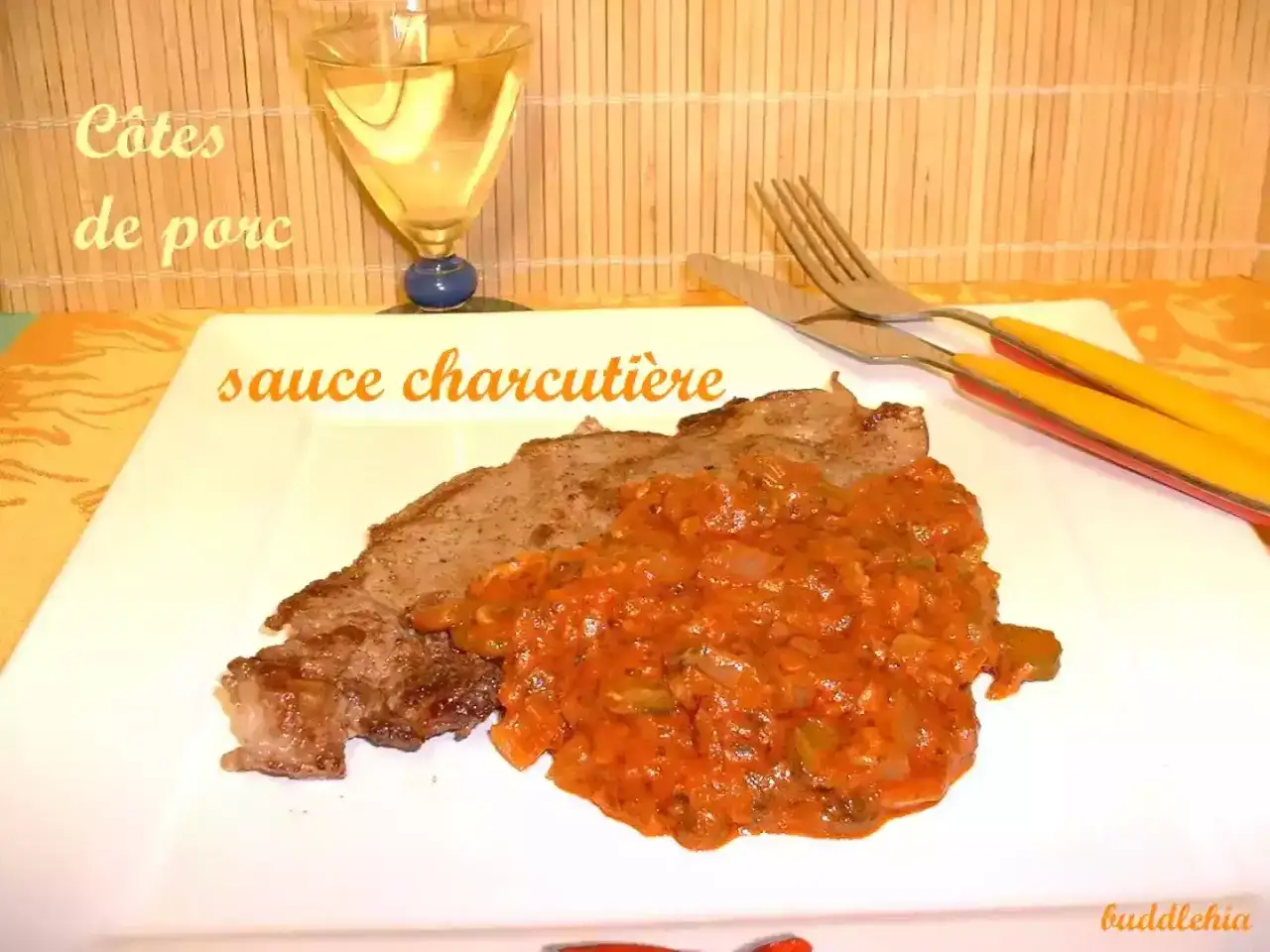 Une côte de porc savoureuse nappée d'une sauce charcutière maison, accompagnée d'un verre de vin blanc.