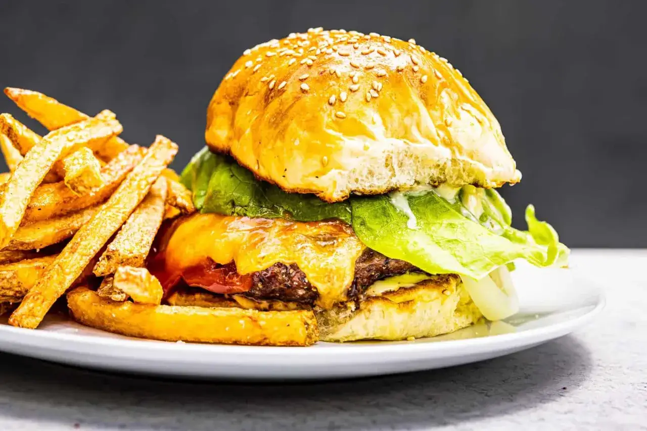 Un délicieux hamburger maison avec fromage fondant, laitue croquante et frites dorées. Une recette parfaite pour un repas gourmand.