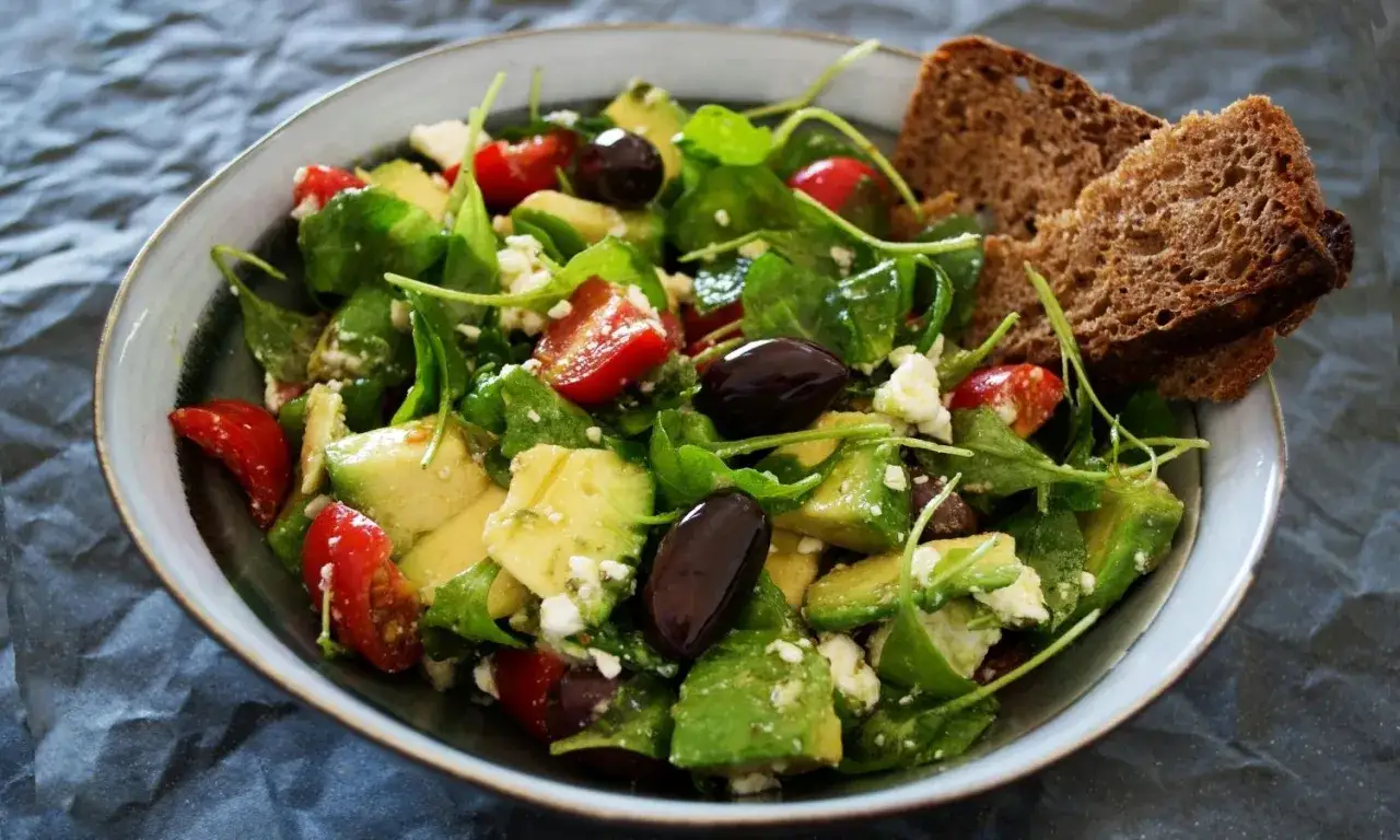 Salade verte garnie d'avocat, tomates cerises, olives noires et feta. Parfait pour savoir quoi mettre dans une salade verte.