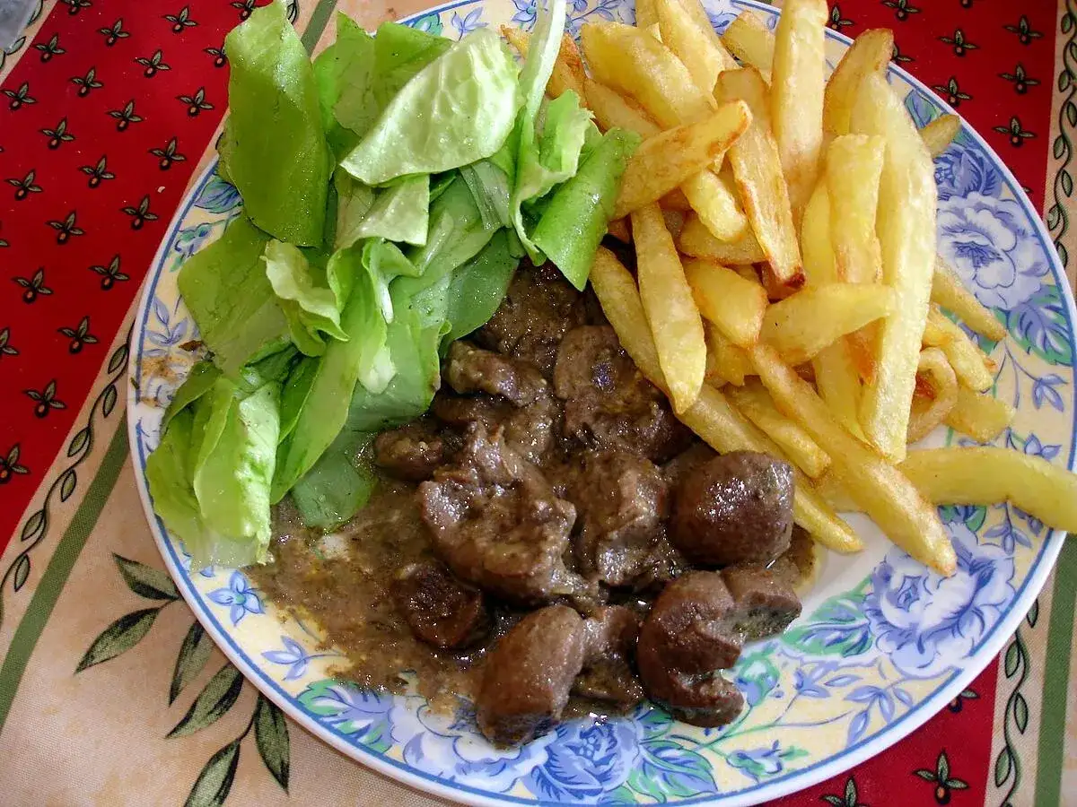 Assiette de rognon de boeuf en sauce, frites dor&eacute;es et salade verte fra&icirc;che. Un plat savoureux pour les amateurs de gibier.