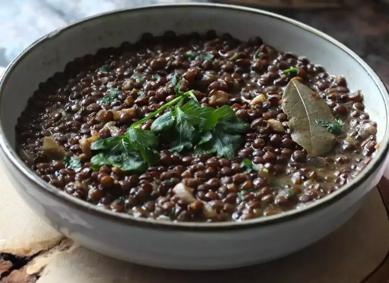 Un plat de cuisson lentilles vertes, garni de persil frais et d'une feuille de laurier.