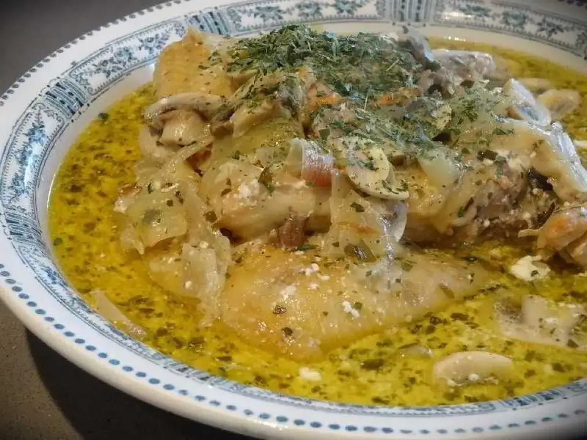 Un plat de fricassée de volaille crémeuse avec des champignons et des herbes, servi dans une assiette décorée.