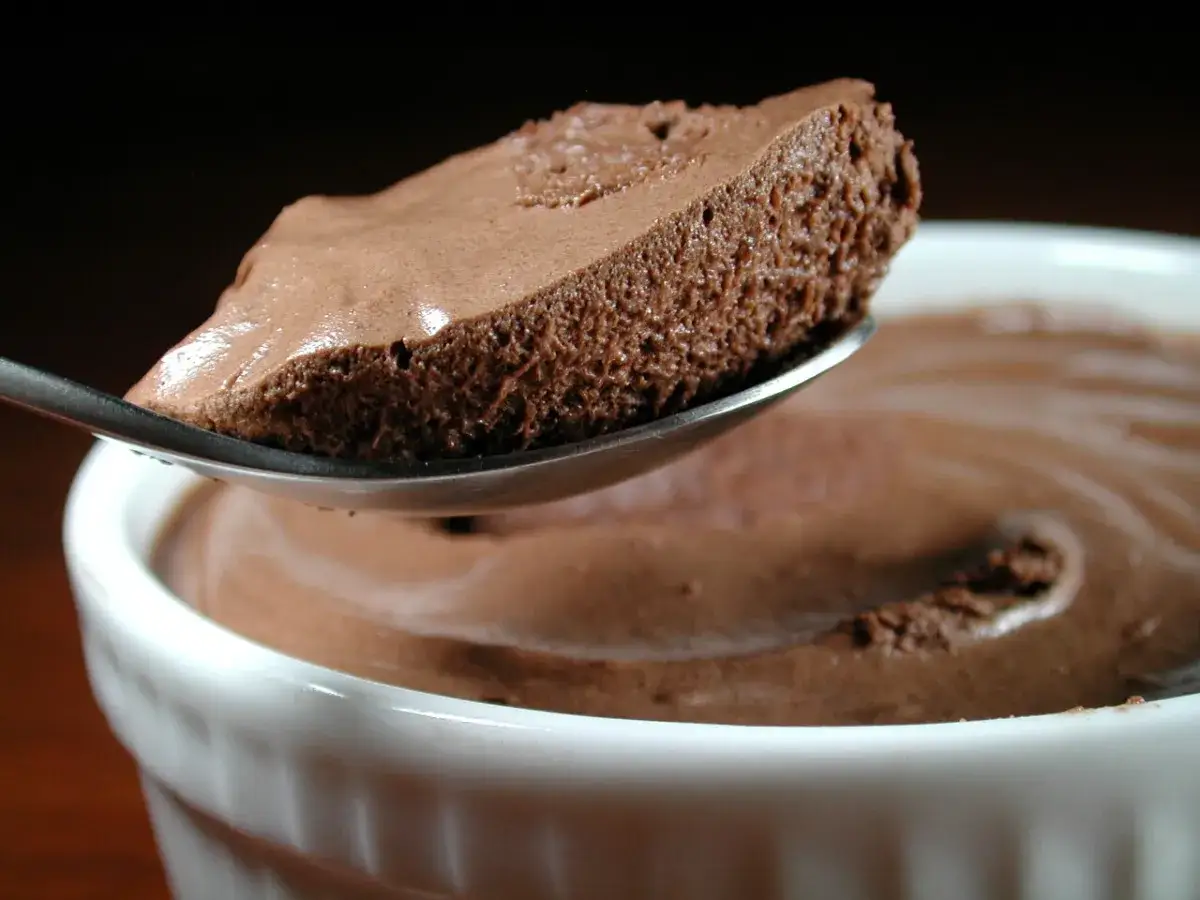 Une cuillère de mousse au chocolat rapide, aérienne et onctueuse, sort d'un ramequin blanc.