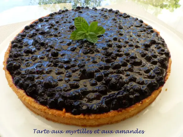 Tarte myrtille amande, une gourmandise aux myrtilles juteuses et à la pâte sablée aux amandes, décorée d'une touche de menthe fraîche.