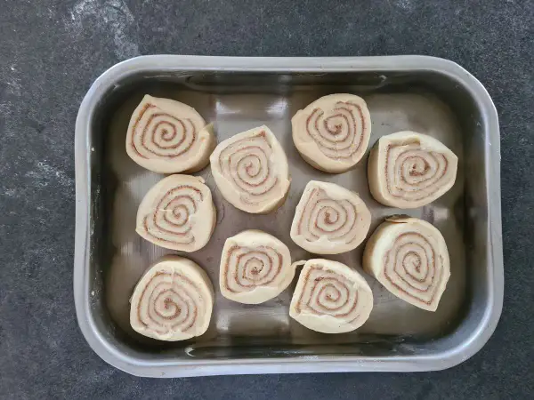 Dix roulés à la cannelle prêts pour la cuisson, une étape clé de la recette de cinnamon rolls.